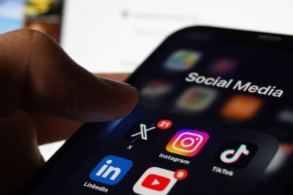 A person holding a smart phone with social media on the screen